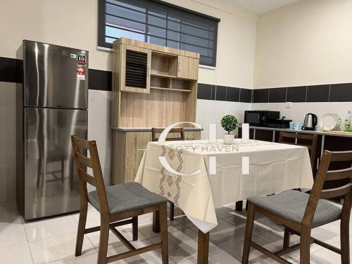 La cuisine est équipée d'une table et d'un réfrigérateur en acier inoxydable. dans l'établissement King bed Kuching Stutong Heights Apartment Nearby Airport, à Kuching