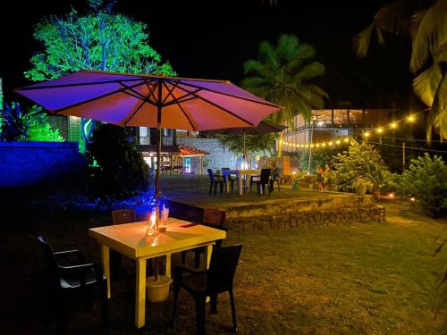 a table with a candle and an umbrella at night at Emma's Sea View in Hiriketiya