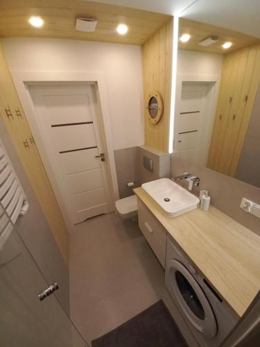 a bathroom with a sink and a washing machine at Apartament u Szkutnika in Puck