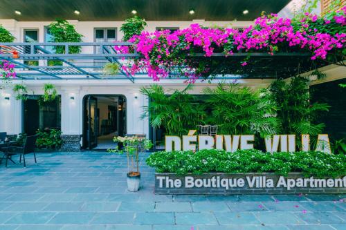 un edificio con flores y un cartel que dice villa negativa en Dérive Boutique Villa & Apartment Da Nang en Da Nang