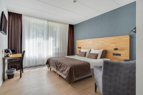 um quarto de hotel com uma cama e uma cadeira em Hotel Bieze em Borger