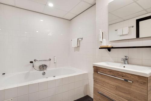 La salle de bains blanche est pourvue d'une baignoire et d'un lavabo. dans l'établissement Hotel Bieze, à Borger