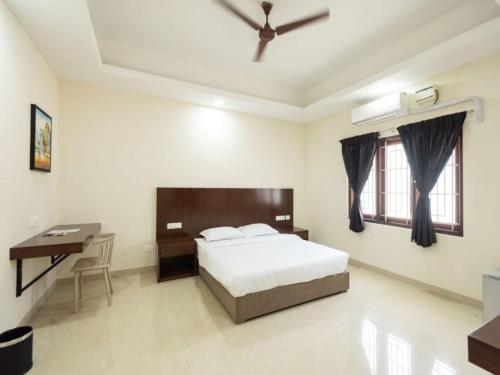 a bedroom with a bed and a desk in it at Mayfair Service Apartments in Pīlamedu
