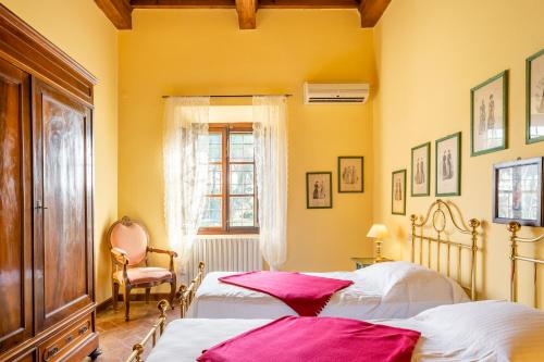 2 łóżka w sypialni z żółtymi ścianami i oknem w obiekcie Villa Rita w mieście Vicopisano