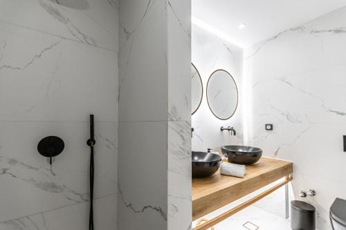 a bathroom with white marble walls and two sinks at Hotel Palatia in Naxos Chora