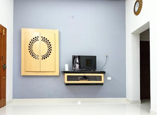 a room with a tv on a blue wall at Meadows Homestay in Madurai