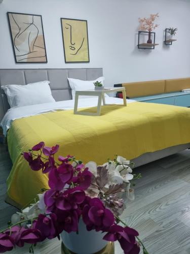 um quarto com uma cama com um cobertor amarelo e flores roxas em Party guesthouse for big groups em Tirana