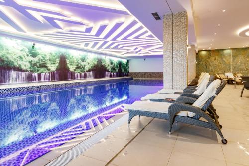 a pool in a hotel lobby with chairs and a swimming pool at Hotel Buket Zlatibor in Zlatibor