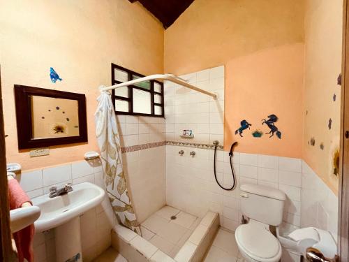 a bathroom with a shower and a toilet and a sink at Hostería EL Trapiche Lodge & Spa in Baños