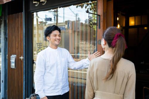 Bamba Hotel Tokyo-Private Townhouse- في طوكيو: رجل يتحدث إلى امرأة خارج متجر