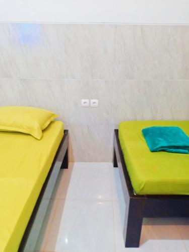 two beds in a room with yellow and green sheets at Homestay Premium 45 in Jepara