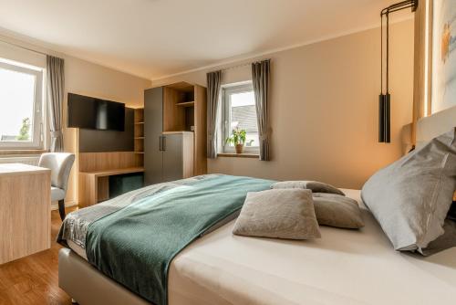 a bedroom with a large bed and a refrigerator at Hotel auszeit Neunkirchen-Seelscheid in Neunkirchen