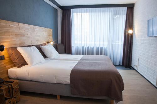 a bedroom with a large bed and a large window at Hotel Bieze in Borger