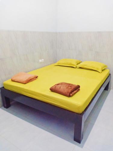 a large yellow bed with two pillows on it at Homestay Premium 45 in Jepara