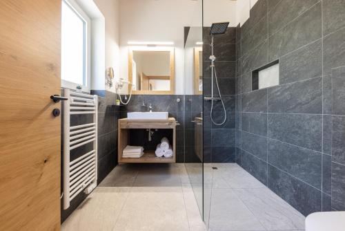 a bathroom with a glass shower and a sink at Apartments am Bichl in Fulpmes