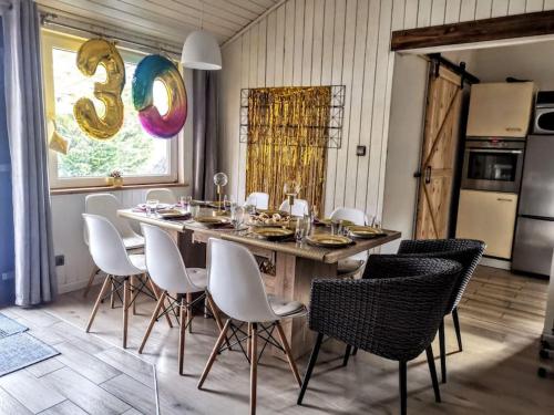 uma sala de jantar com uma grande mesa de madeira e cadeiras brancas em Basiówka nad jeziorem em Boszkowo