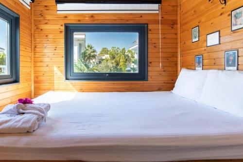 ein großes Bett in einem Holzzimmer mit Fenster in der Unterkunft Alley Tiny House in Fethiye