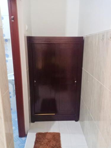 a wooden door in a bathroom with a rug at Homestay Premium 45 in Jepara