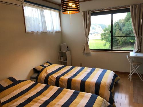 two beds in a room with a window at Share Creative&Bed adonoan in Takeo