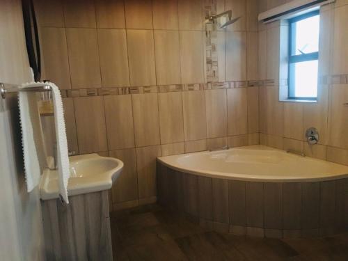 a bathroom with a tub and a sink and a window at Classy Guest House in Johannesburg