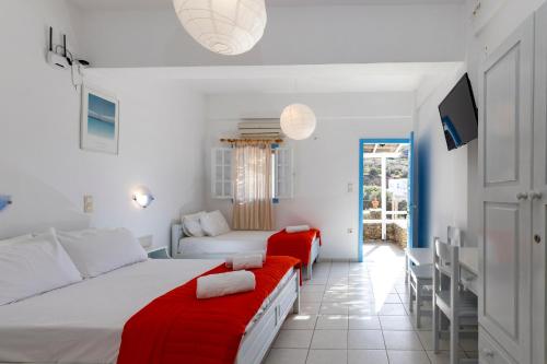 a bedroom with two beds and a red couch at Rita Rooms Sifnos in Platis Gialos