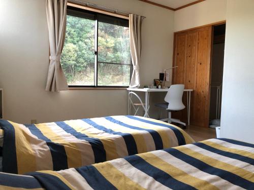a bedroom with two beds and a window at Share Creative&Bed adonoan in Takeo