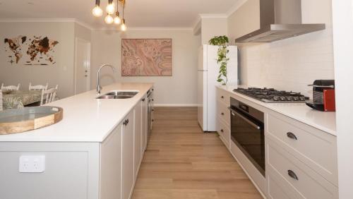 a white kitchen with a sink and a stove at Serenity by the Sea in Busselton