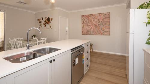 a kitchen with a sink and a refrigerator at Serenity by the Sea in Busselton