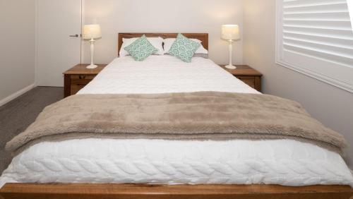 a bedroom with a large white bed with two lamps at Serenity by the Sea in Busselton