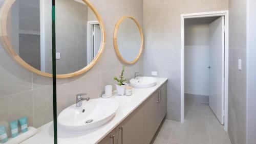 a bathroom with two sinks and two mirrors at Serenity by the Sea in Busselton