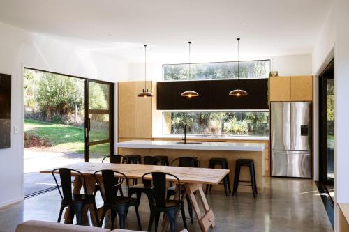 a kitchen with a wooden table and chairs at Modern Raglan Hideaway in Raglan