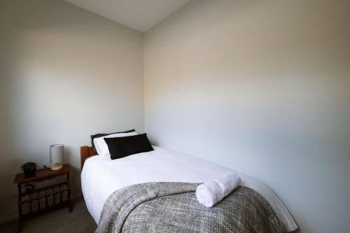 a bedroom with a white bed with a towel on it at Modern Raglan Hideaway in Raglan
