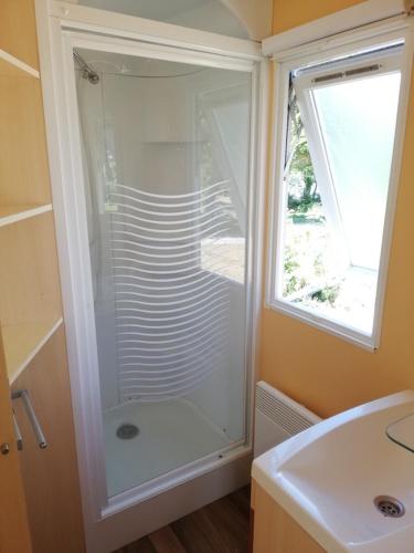 La salle de bains est pourvue d'une douche, d'un lavabo et d'une fenêtre. dans l'établissement Hébergements camping 