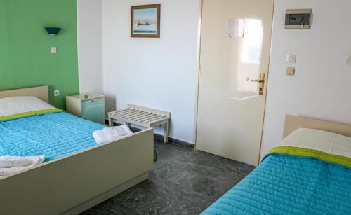 a small bedroom with two beds and a door at Mirtos Hotel in Myrtos