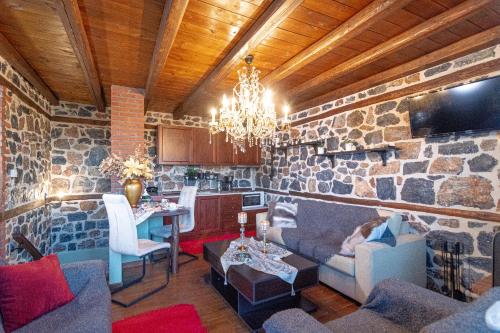 a living room with a stone wall with a chandelier at Palaios Agios Athanasios Luxury Μaisonette in Palaios Agios Athanasios