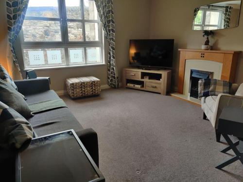 a living room with a couch and a tv and a fireplace at Next to the Palace and Royal Mile with parking in Edinburgh