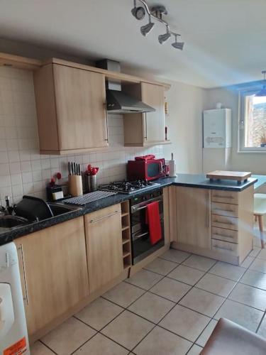 a kitchen with wooden cabinets and a stove top oven at Next to the Palace and Royal Mile with parking in Edinburgh