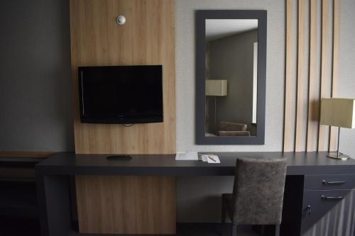 a hotel room with a desk with a tv and a mirror at Hotel Anatolia in Bursa