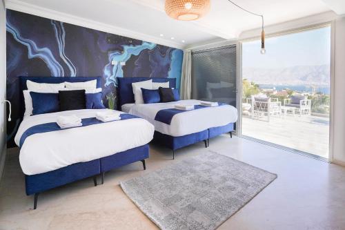 two beds in a room with a large window at Yalarent Enorma complex with shared heated pool in Eilat