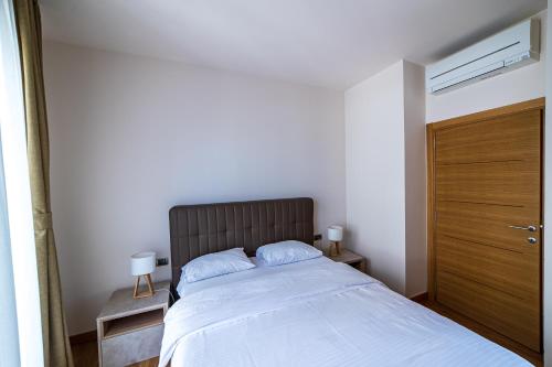 a bedroom with a large bed with a wooden door at Elite apartments Podgorica in Podgorica