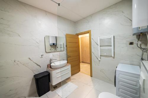 a white bathroom with a sink and a toilet at Elite apartments Podgorica in Podgorica