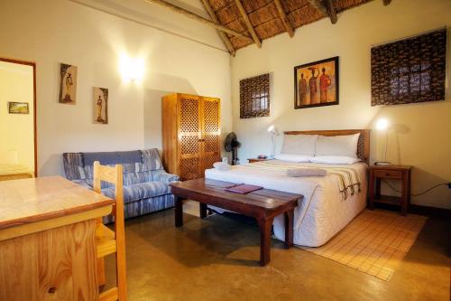 1 dormitorio con cama, mesa y sofá en Rosedale Organic Farm Bed & Breakfast, en Addo