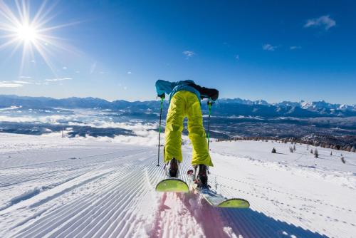 a person is standing on skis in the snow at Blaues Haus Ferienwohnung Bodensdorf Ossiacher See Gerlitzen Alpe in Bodensdorf