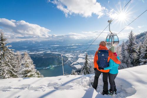 two people riding a ski lift on a snow covered mountain at Blaues Haus Ferienwohnung Bodensdorf Ossiacher See Gerlitzen Alpe in Bodensdorf