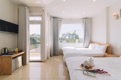a hotel room with two beds and a balcony at Khách sạn Thanh Thùy Đà Lạt in Xuan An