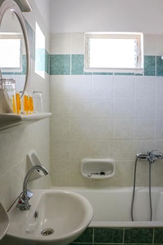a bathroom with a sink and a tub with a mirror at Mirtos Hotel in Myrtos