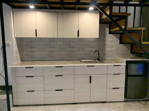 una cocina con armarios blancos y fregadero en JORA LOFT- modern industrial apartment 1-A en Dagupan