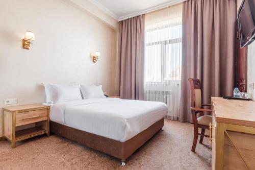 une chambre d'hôtel avec un lit et un bureau dans l'établissement Western Suites Hotel, à Tachkent