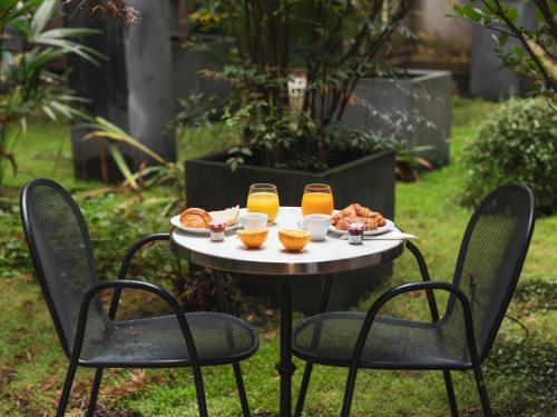 een tafel met een dienblad met eten en glazen sinaasappelsap bij Le Rayz Vendome in Parijs