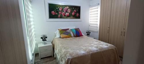 1 dormitorio con 1 cama y una pintura en la pared en Apartamento en Valle de lili, en Cali